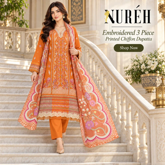 A woman models an orange embroidered 3-piece traditional outfit with a matching printed dupatta while walking down a grand white marble staircase. The set features intricate embroidery and colorful floral patterns in pink, purple, and gold.